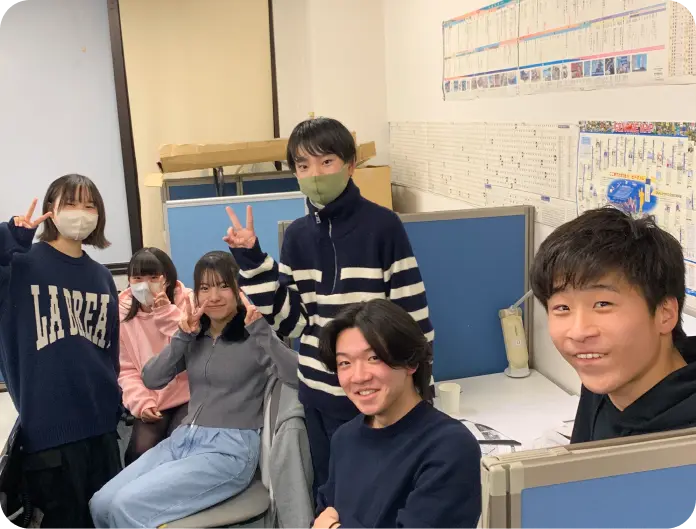 塾の教室でピースサインの生徒たちの集合写真